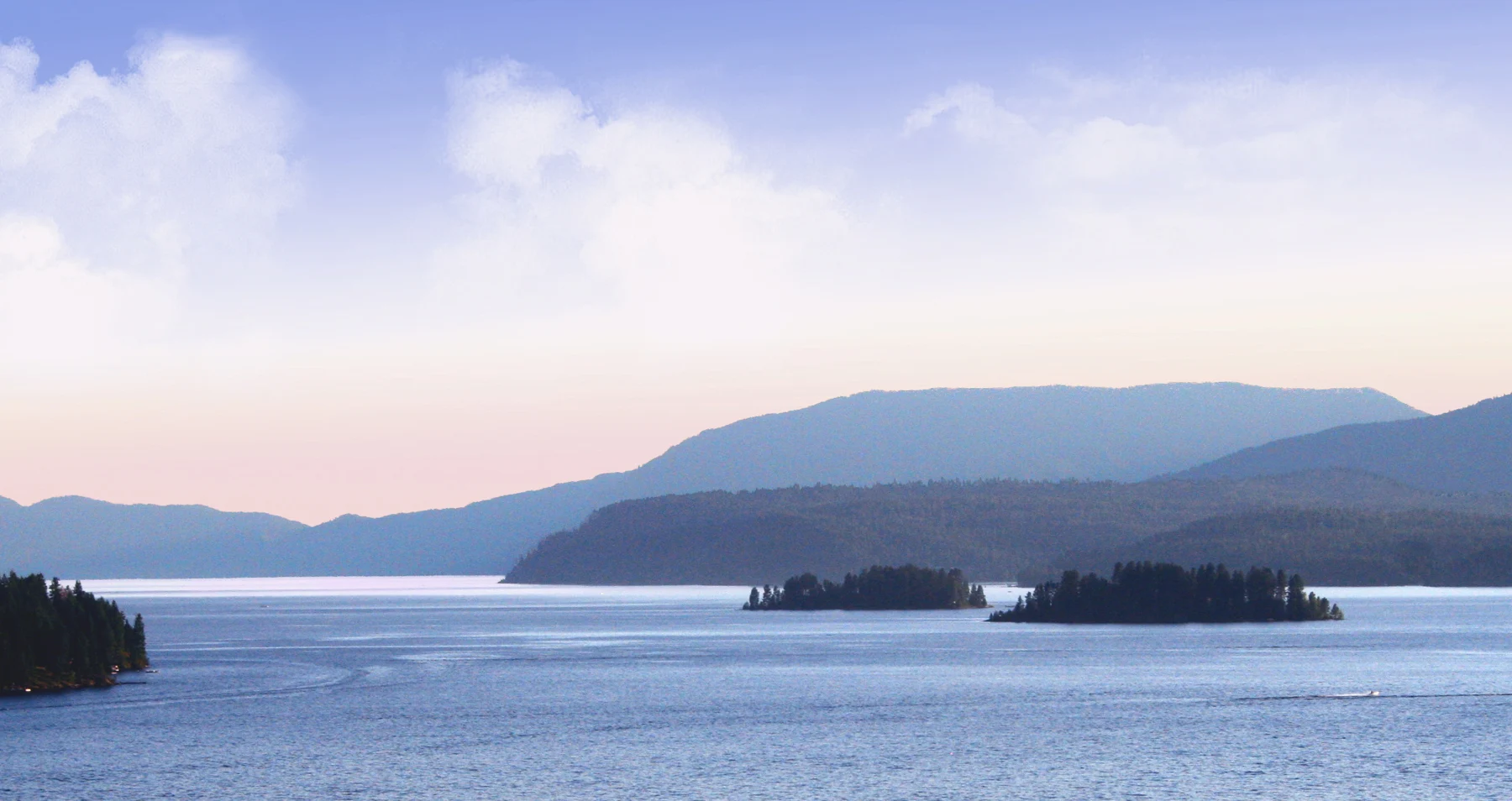 Islands and mountains across the lake beneath a pastel sky